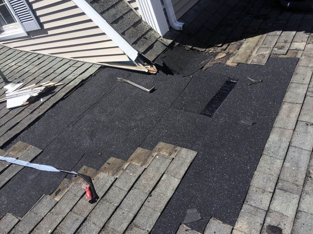 Close-up of roof with damaged shingles and flashing, indicating potential leak areas on a residential roof.