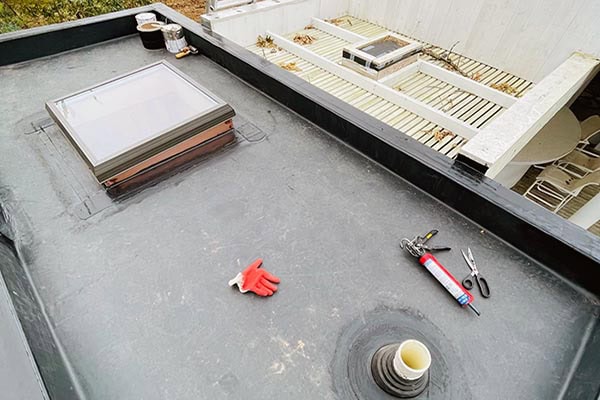 Roofing and chimney repair work on a flat rooftop in Long Island, NY, with tools and materials ready for installation or maintenance.