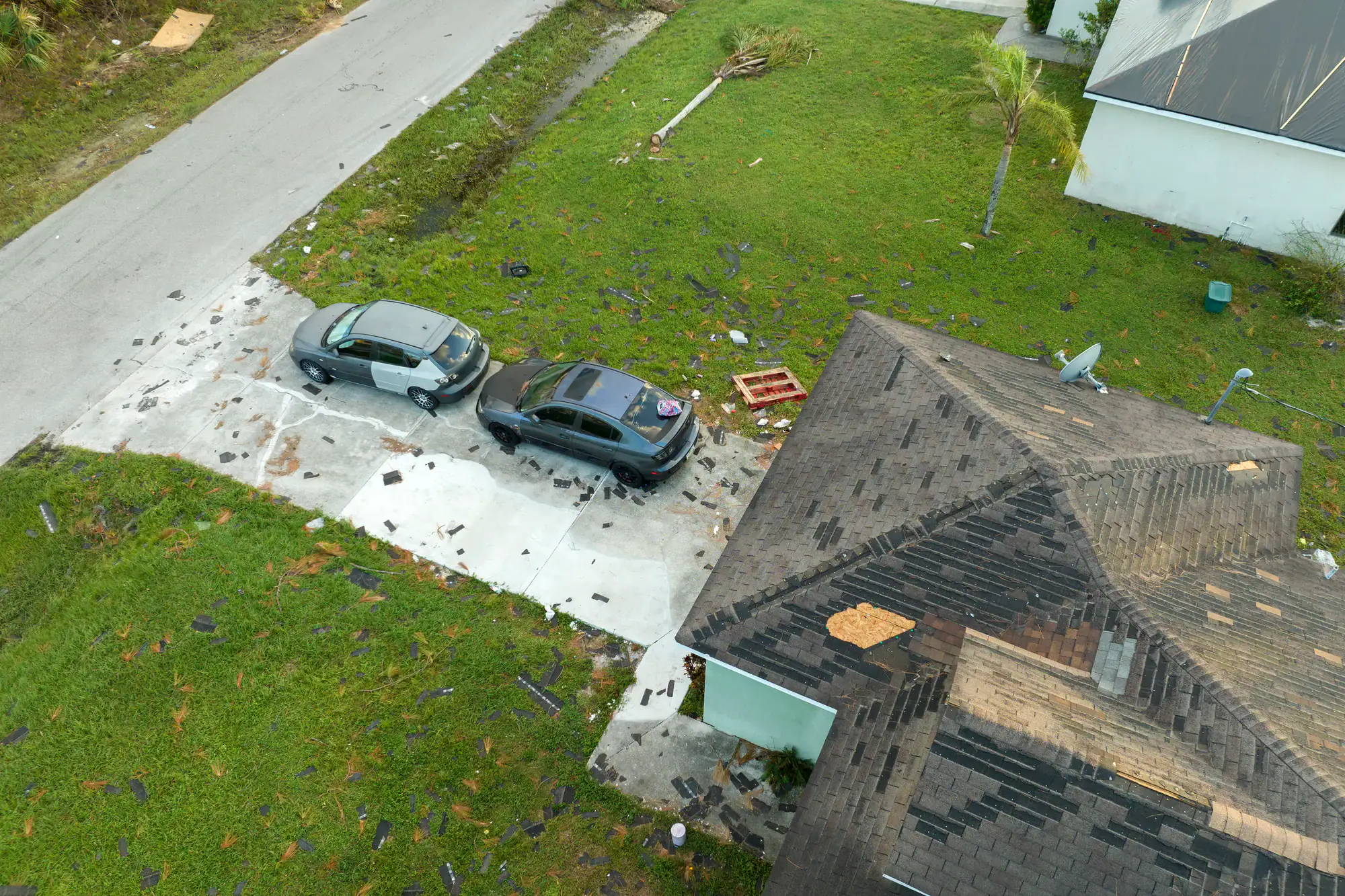 Roof damage repair after storm in Long Island, NY, showing roof and driveway damage.