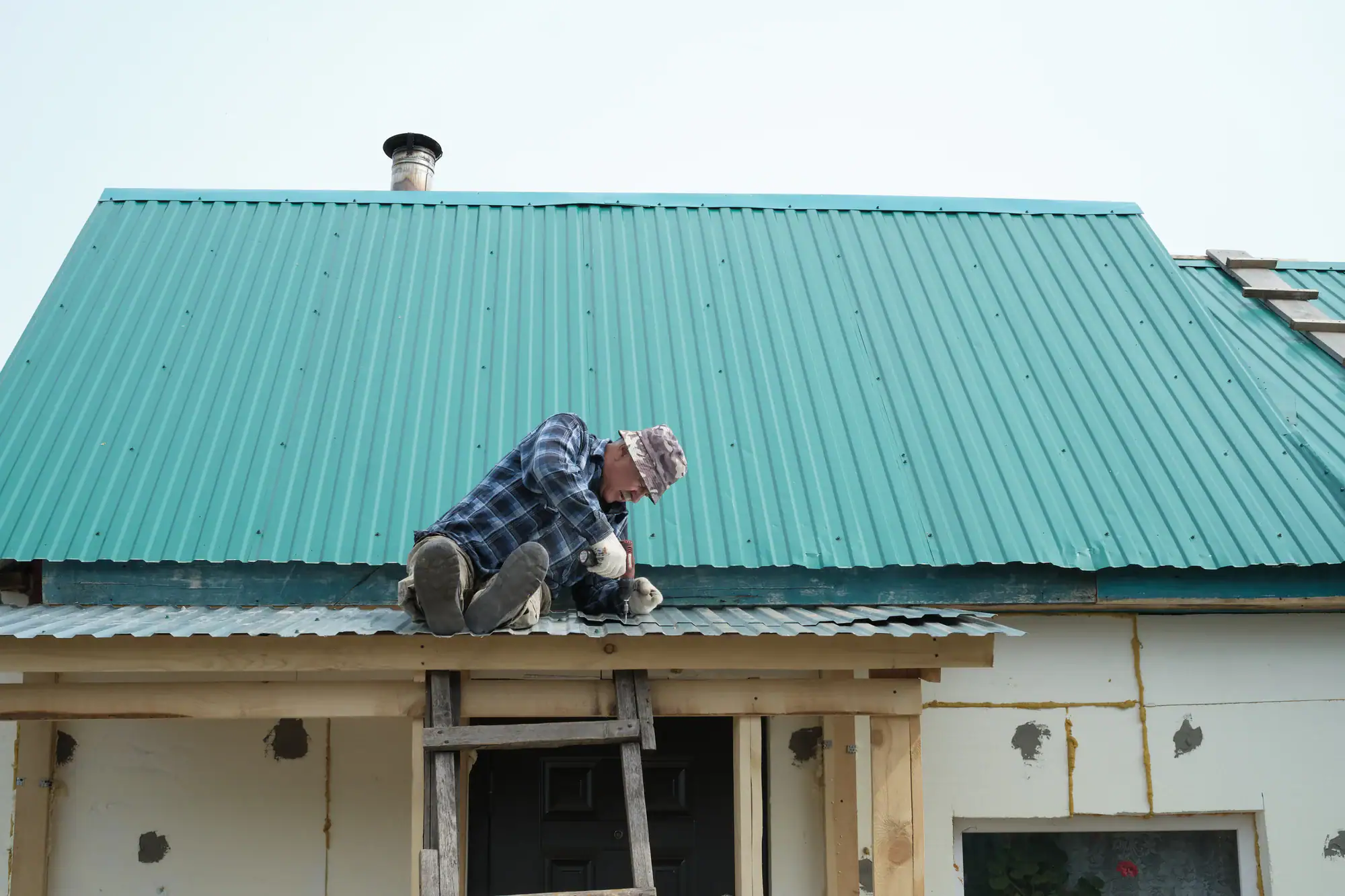 Skilled roofer installing new metal roofing on a residential house in Long Island, NY, ensuring durability and weather resistance.