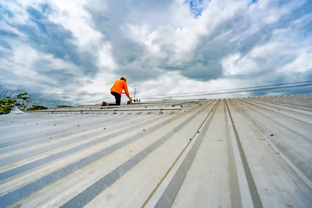Worker inspecting a metal roof on a cloudy day in Long Island, NY.